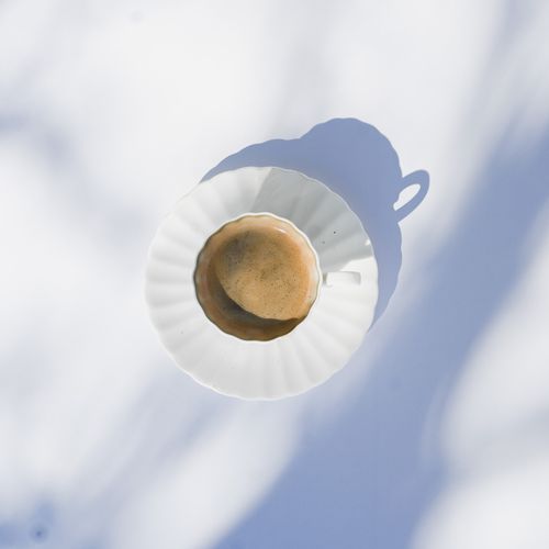 Free Top view of a coffee cup casting a shadow on a white background, minimal style. Stock Photo