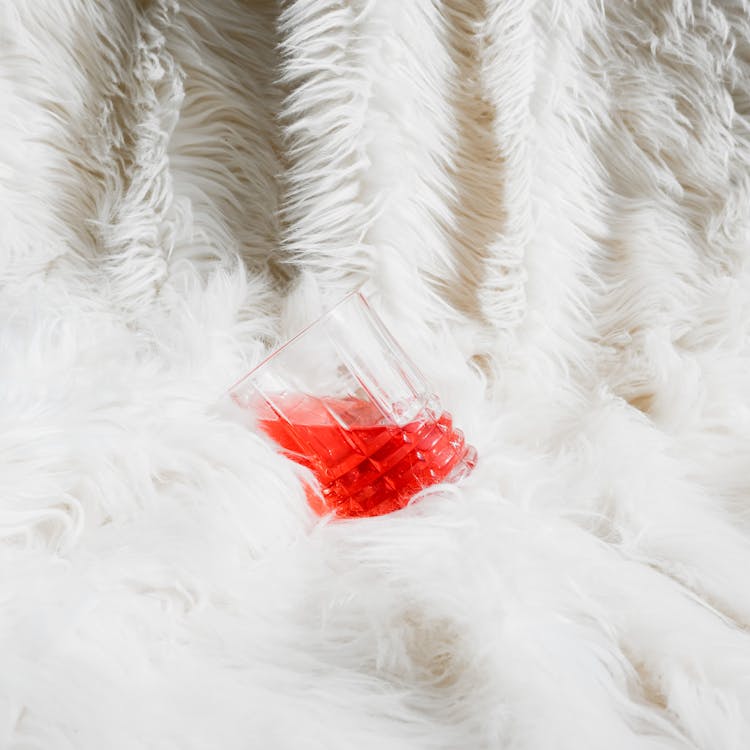 Crystal Glass With A Red Drink On A White Fur