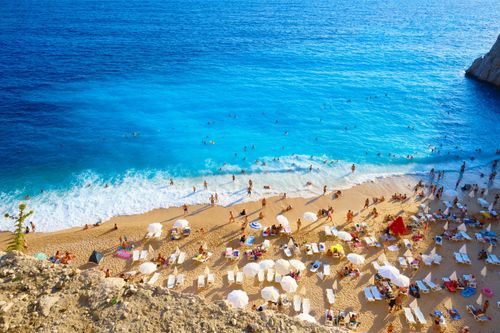 Free Aerial view of a crowded beach with sunbathers and umbrellas on a sunny summer day. Stock Photo