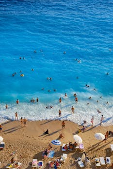 Vibrant aerial photo of people enjoying a sunny day at a crowded beach, swimming and relaxing.