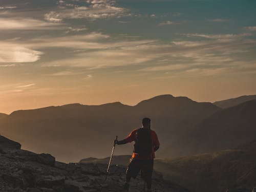 Back View of a Man Hiking in Mountains at Sunset