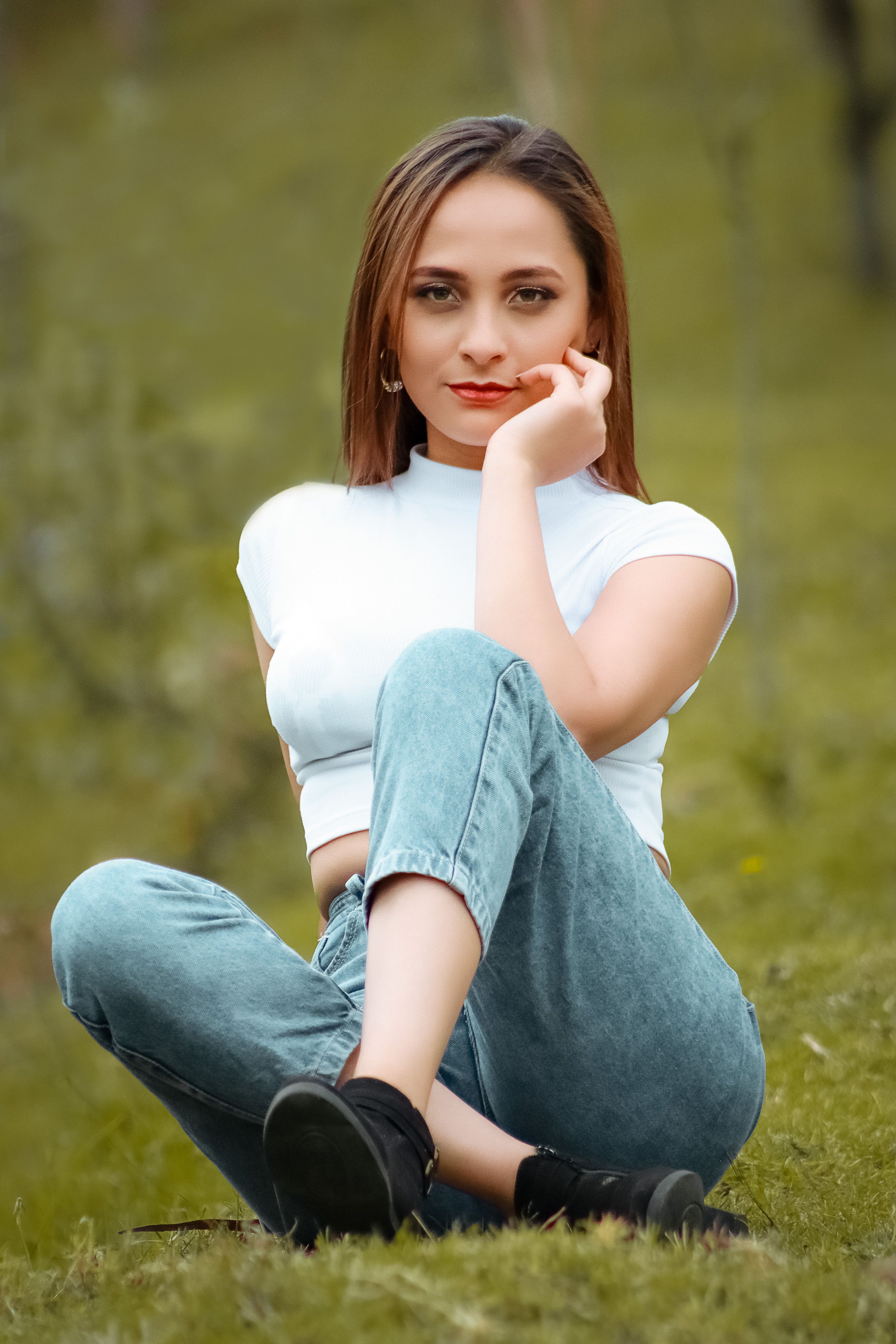 Portrait of a woman in jeans and white blouse posing outdoors.