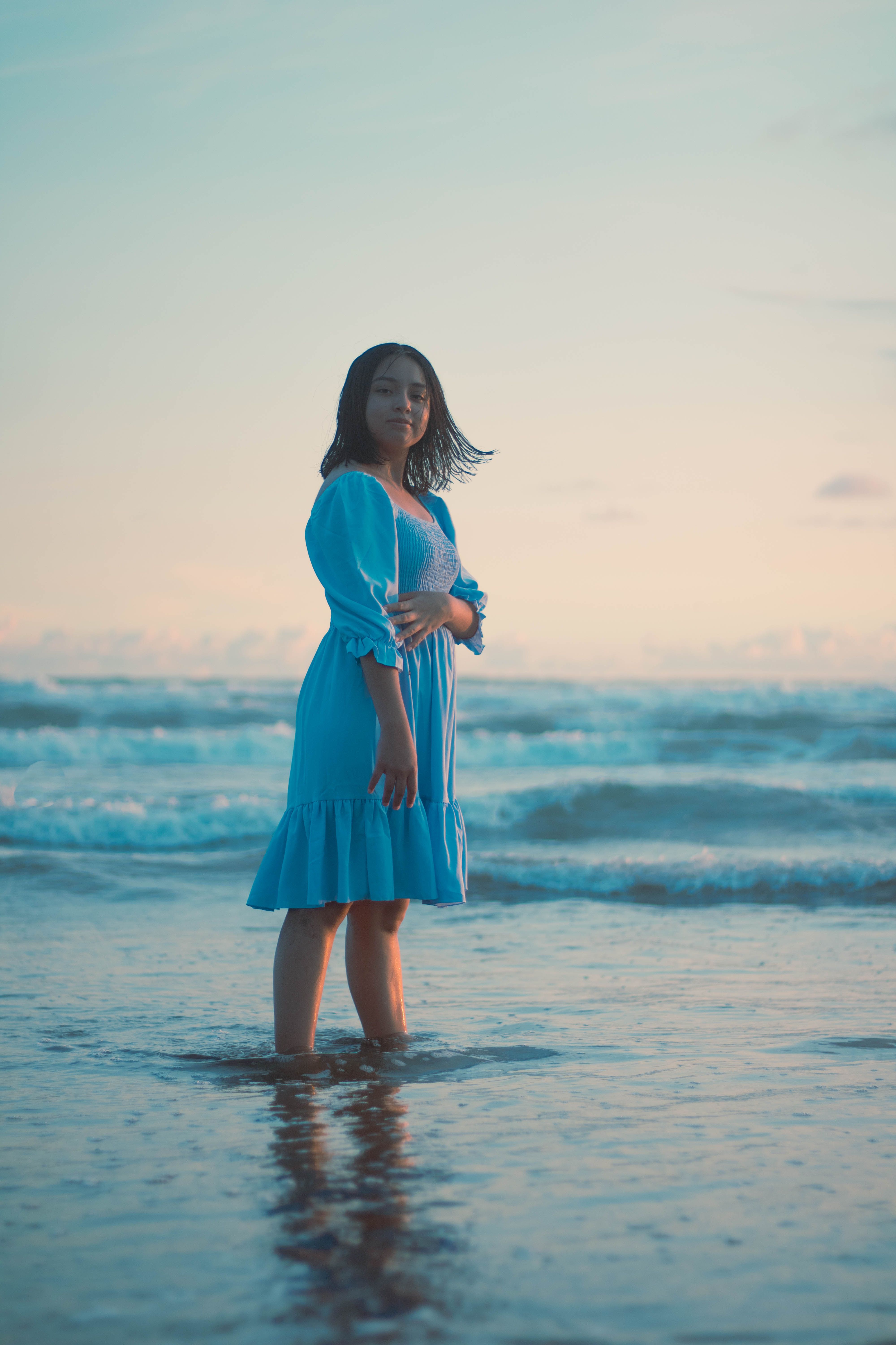 Girl Wearing Blue Dress Standing in the Sea at Dusk · Free Stock Photo