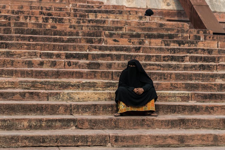 Woman In Niqab And Abaya Sitting On Stairs