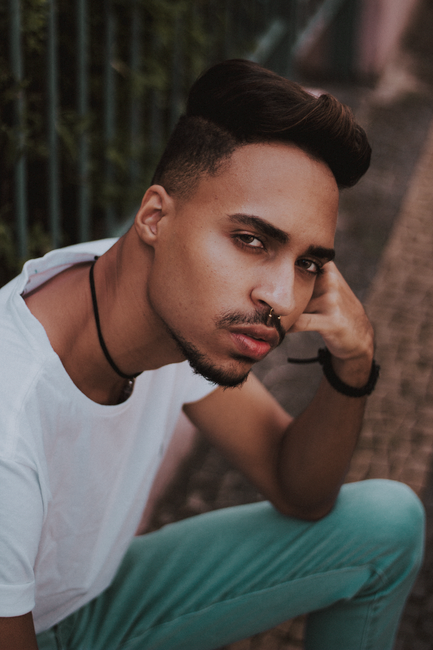 Portrait of a fashionable man with a nose ring outdoors, wearing a white t-shirt and blue jeans.