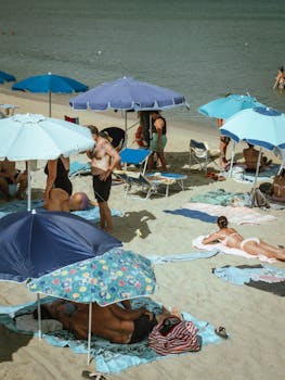 A lively beach scene featuring colorful umbrellas and people relaxing by the seaside.