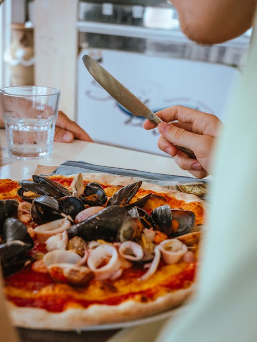 Hand with Knife over Pizza