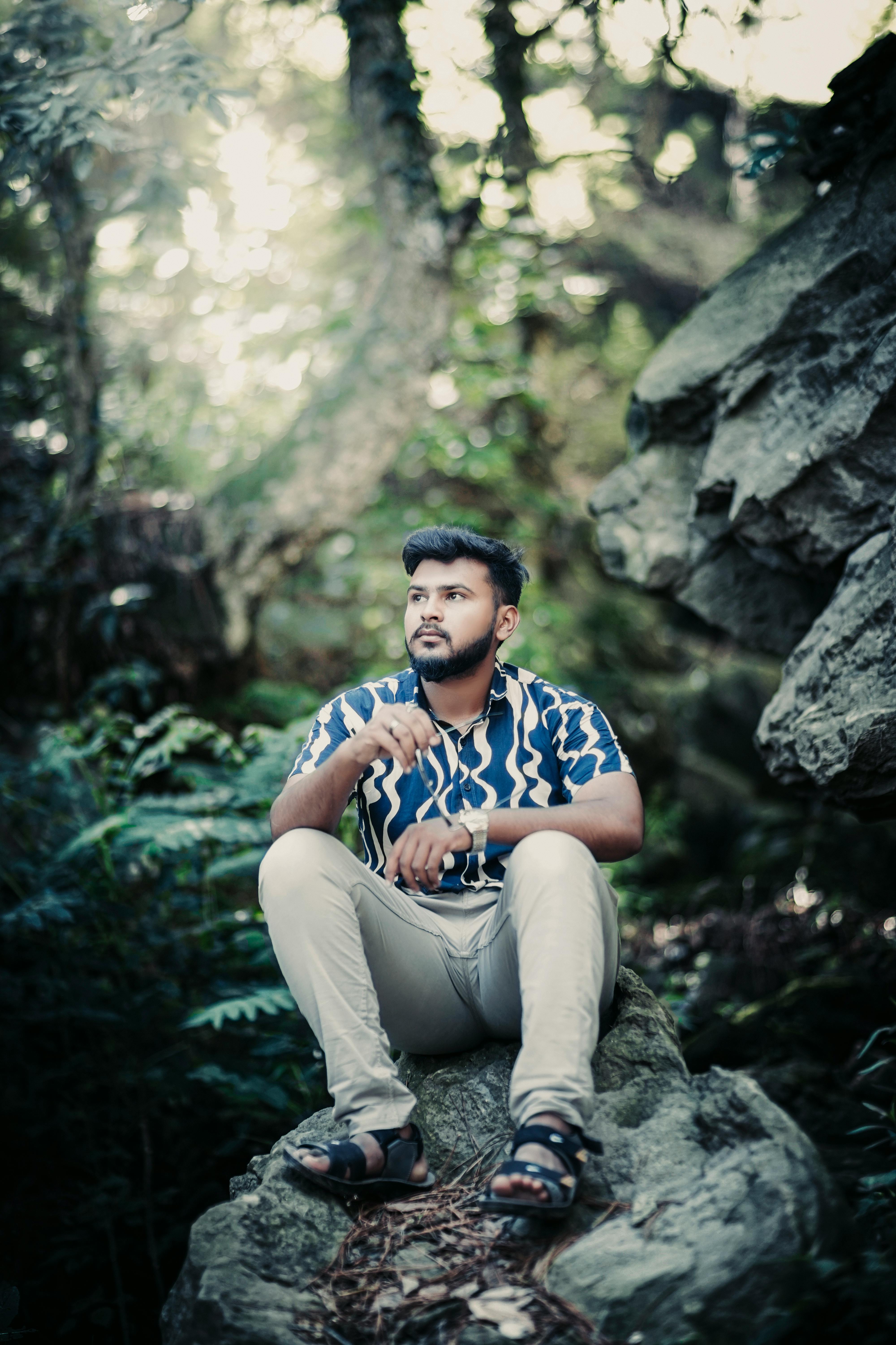 man sitting on rock in forest