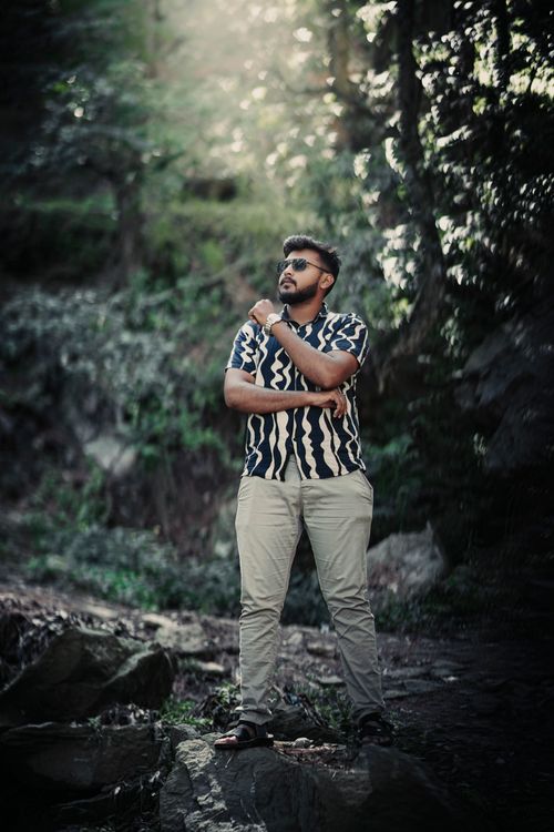 Free Stylish man wearing sunglasses poses confidently in a forest setting. Stock Photo
