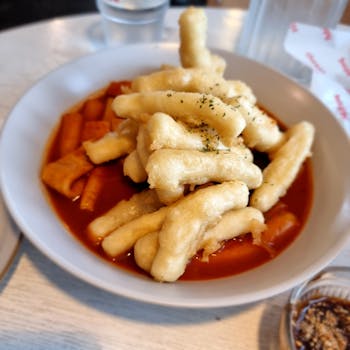 A savory plate of Korean tteokbokki topped with crispy tempura, perfect for food photography enthusiasts.