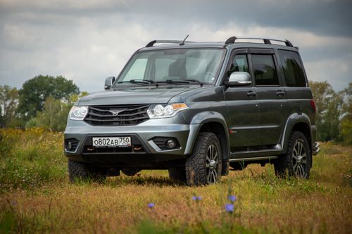 Free Silver UAZ SUV parked in a scenic rural meadow, showcasing rugged design. Stock Photo