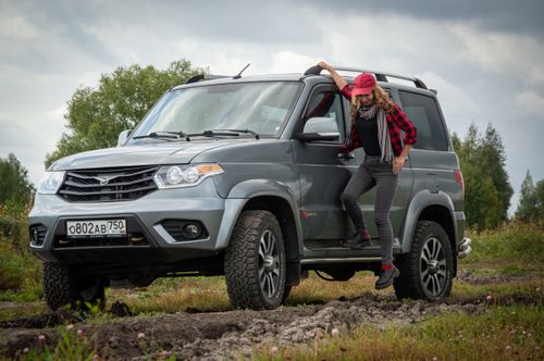 Free A woman in a cap leaning on a rugged SUV off road in a natural setting. Stock Photo