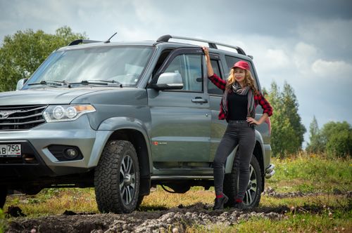 Free A stylish woman stands confidently beside an off-road SUV in a natural landscape. Stock Photo