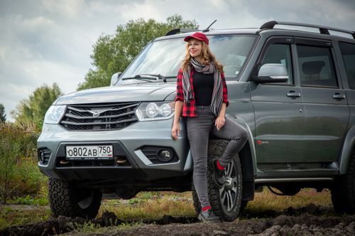 Free A woman stands by an SUV in a rural field, embodying adventure and exploration. Stock Photo