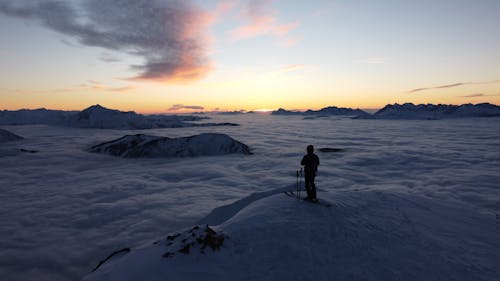 Person on Hilltop over Clouds below in Mountains in Winter