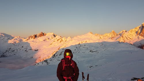 Person in Jacket and Goggles in Mountains at Sunset