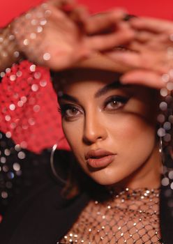 Elegant woman posing in a fashion shoot with metallic details and a striking red background.