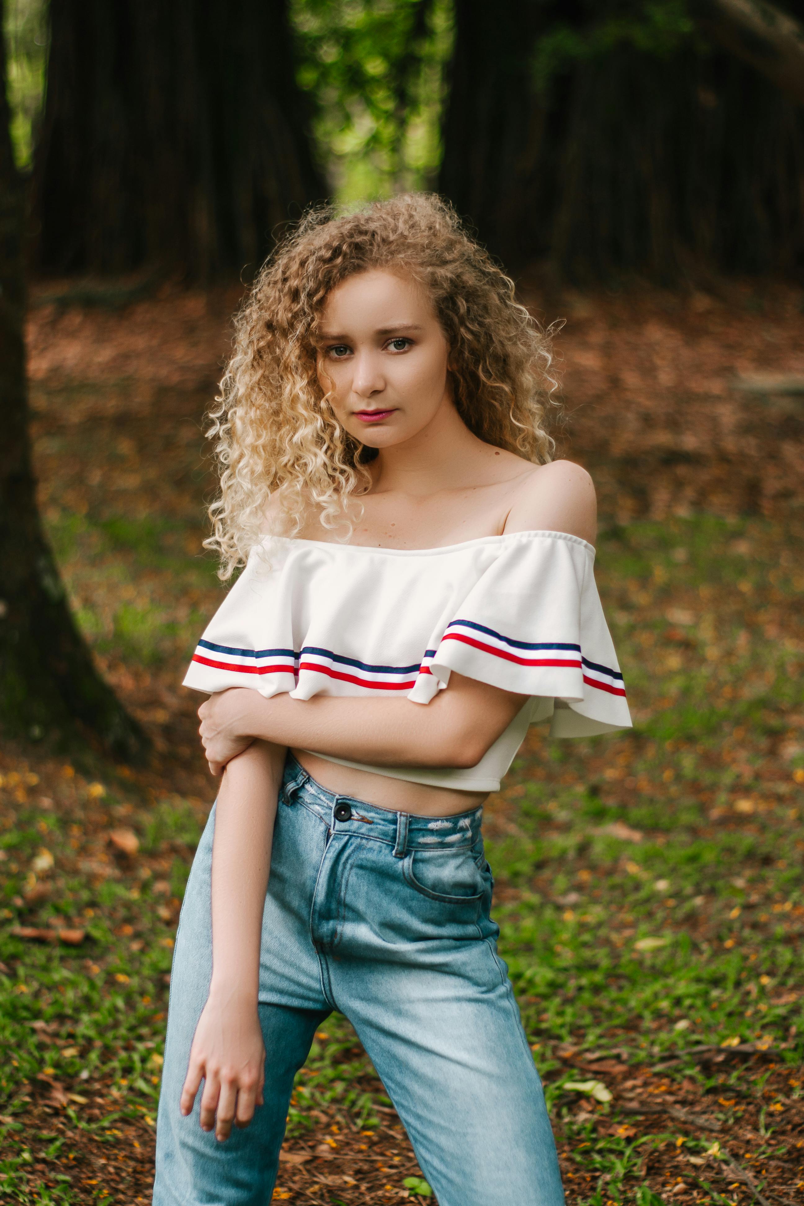Woman in White Off-shoulder Crop Top and Blue Jeans