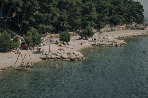 Free People relaxing on a sunny beach surrounded by trees and calm water. Stock Photo