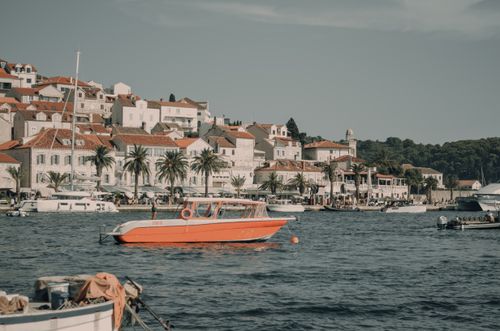 Free View of Hvar, Croatia's charming coastal cityscape with orange motorboat and yachts in the harbor. Stock Photo