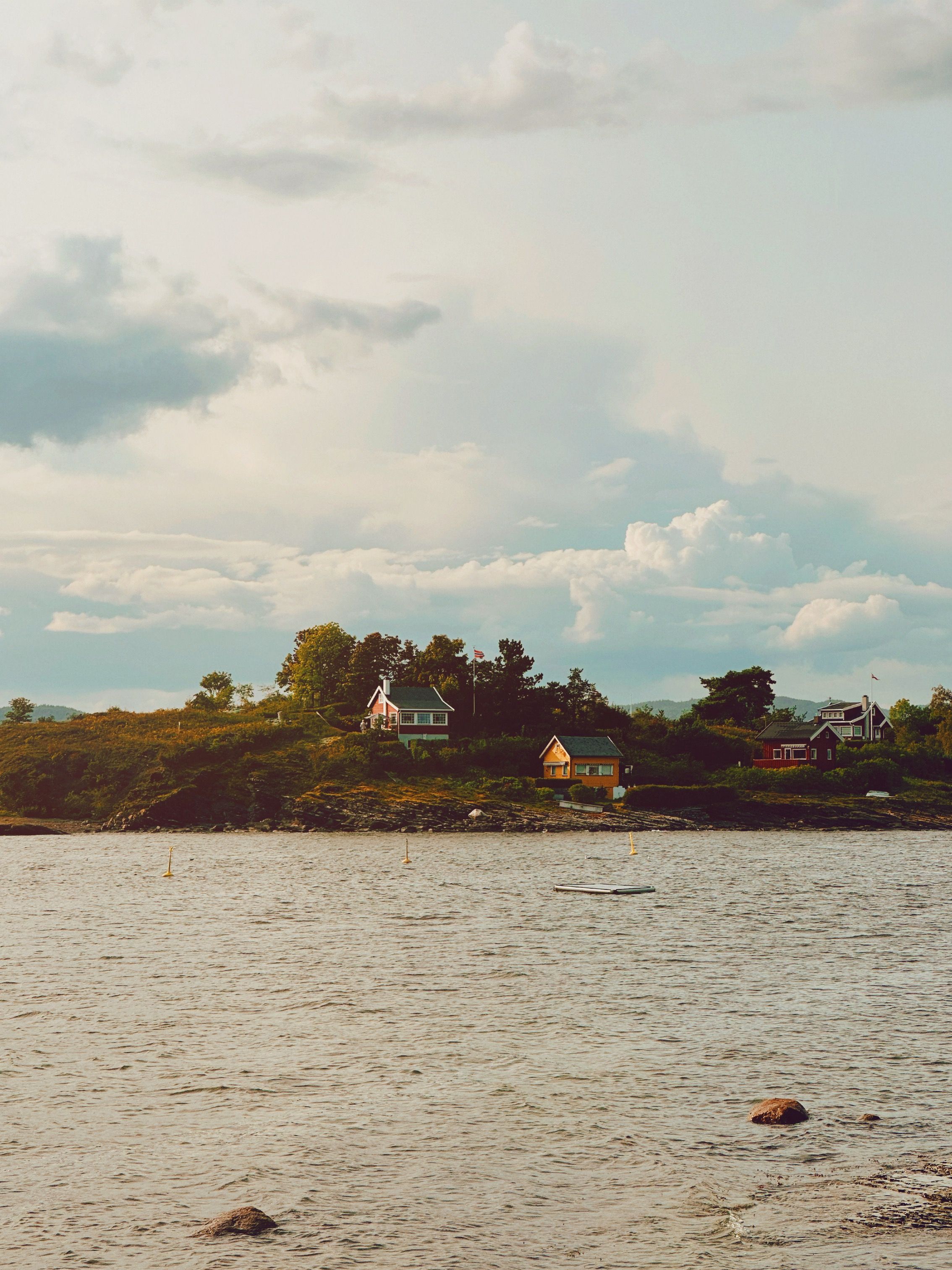 Picturesque village by a lake in Oslo, Norway. Serene landscape with houses and lush greenery.