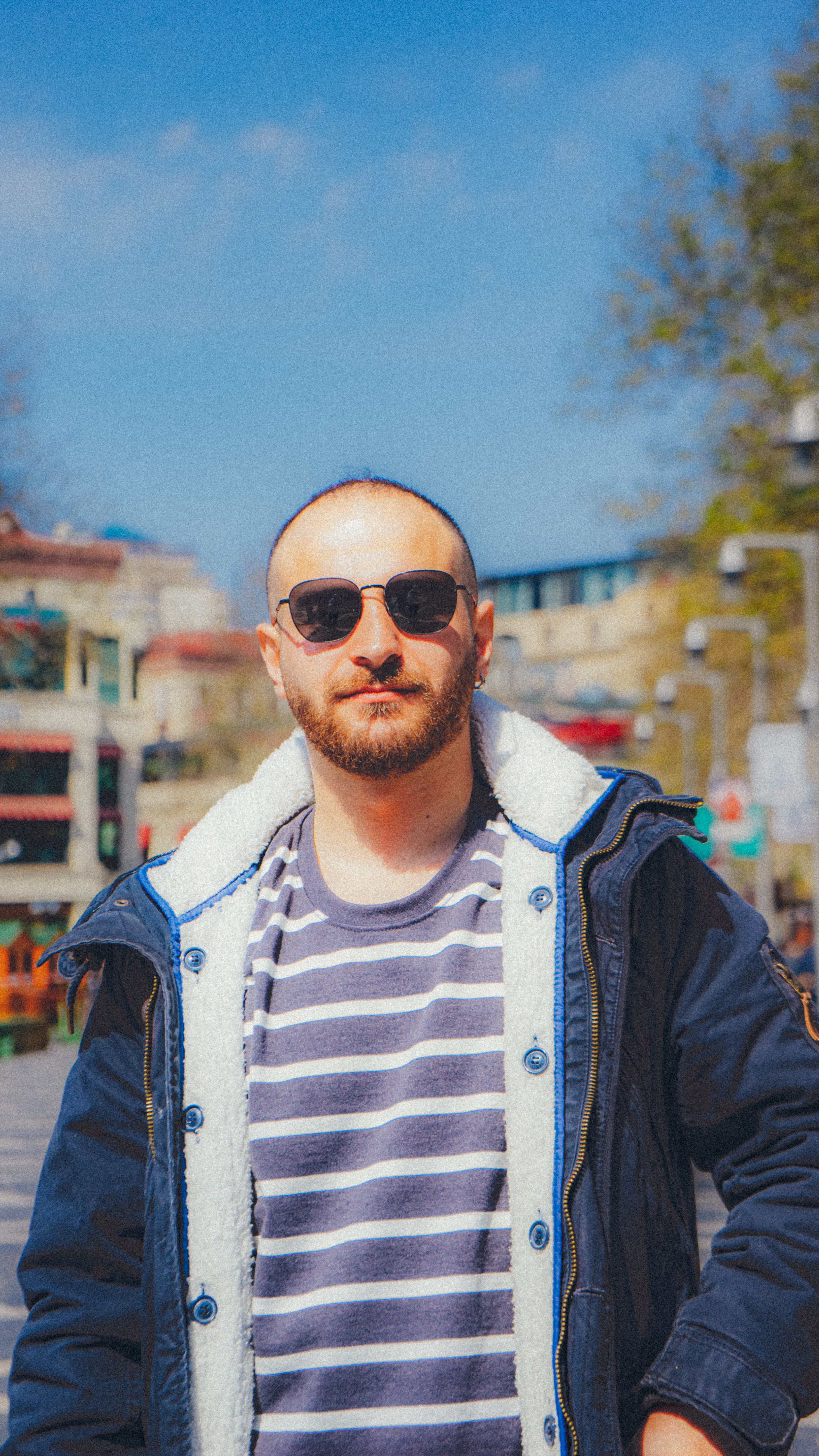Portrait of a man in a blue jacket and sunglasses standing outdoors on a sunny day in Baku.