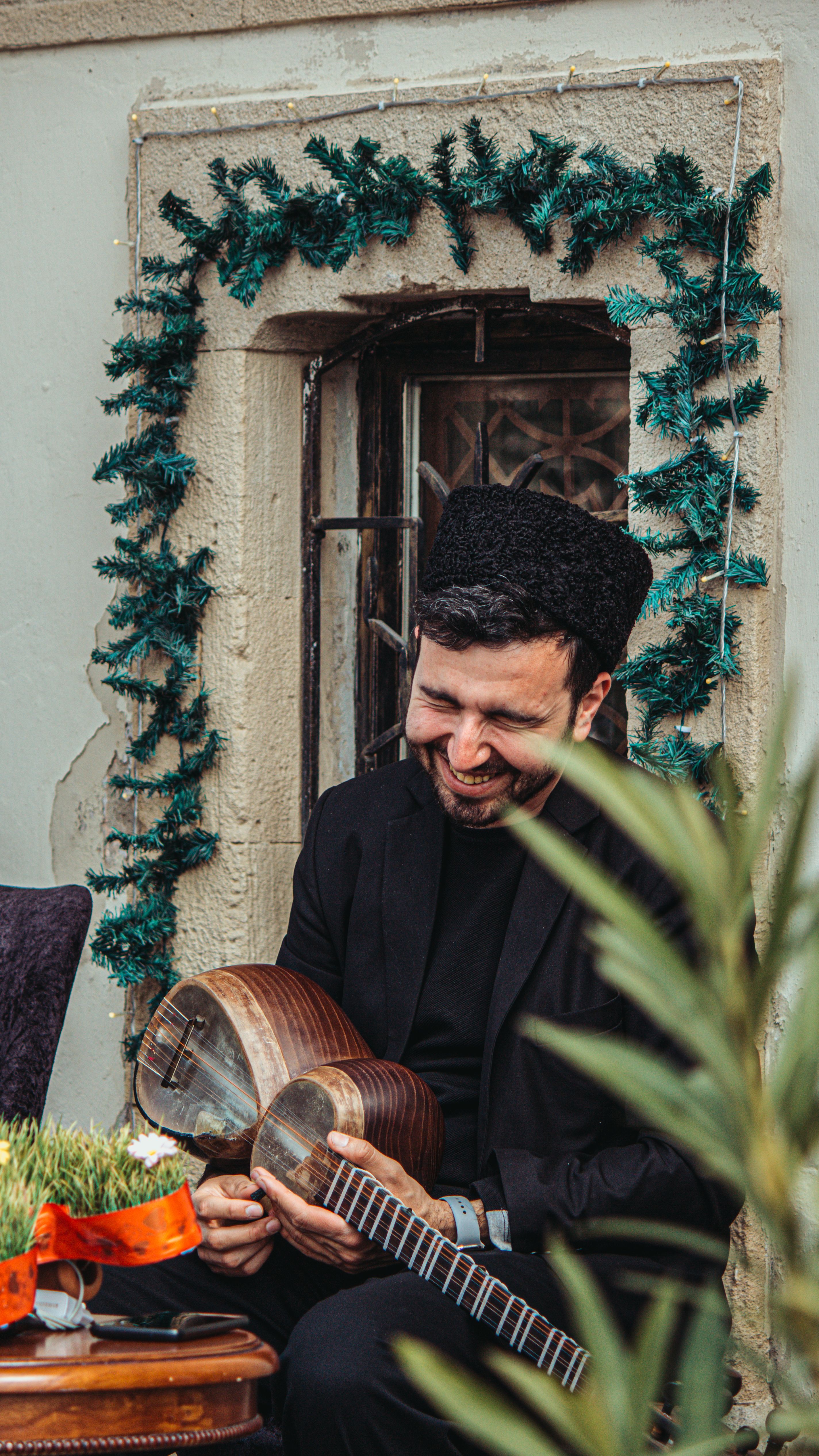 A smiling musician in Azerbaijan holding a tar, wearing traditional attire.