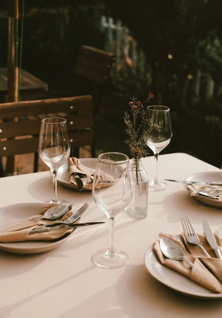 Chic outdoor dining setup in Đà Lạt with cutlery, plates, and wine glasses under warm lighting.