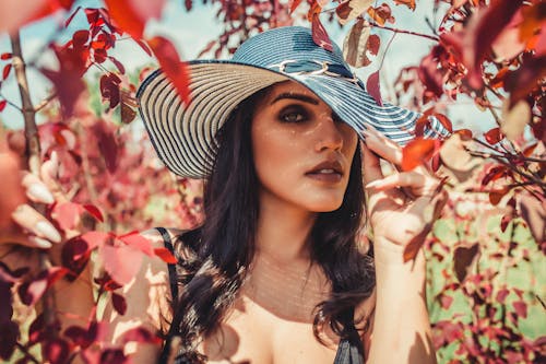 Femme Portant Un Chapeau De Soleil Tout En étant Entouré De Feuilles Rouges à L'extérieur