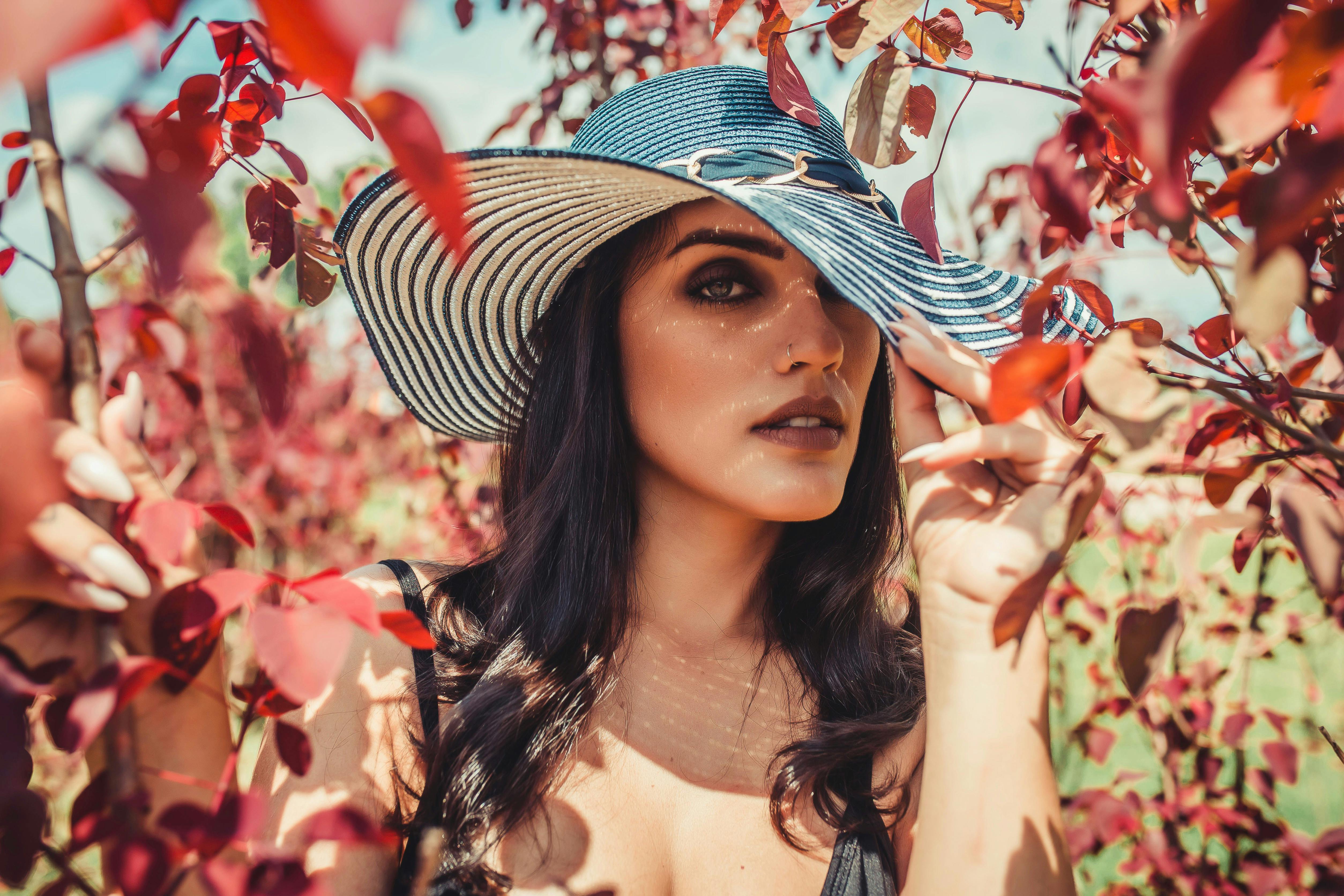Woman Wearing Sun Hat While Being Surrounded by Red Leaves Outdoors