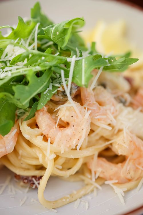 Free Delicious creamy shrimp pasta topped with fresh arugula and grated Parmesan cheese. Stock Photo