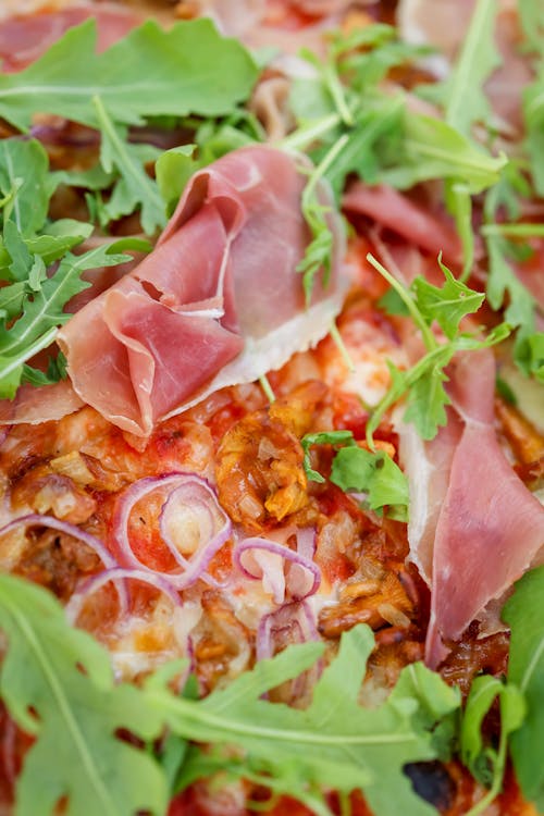 Close-Up Photo of a Pizza with Prosciutto and Arugula