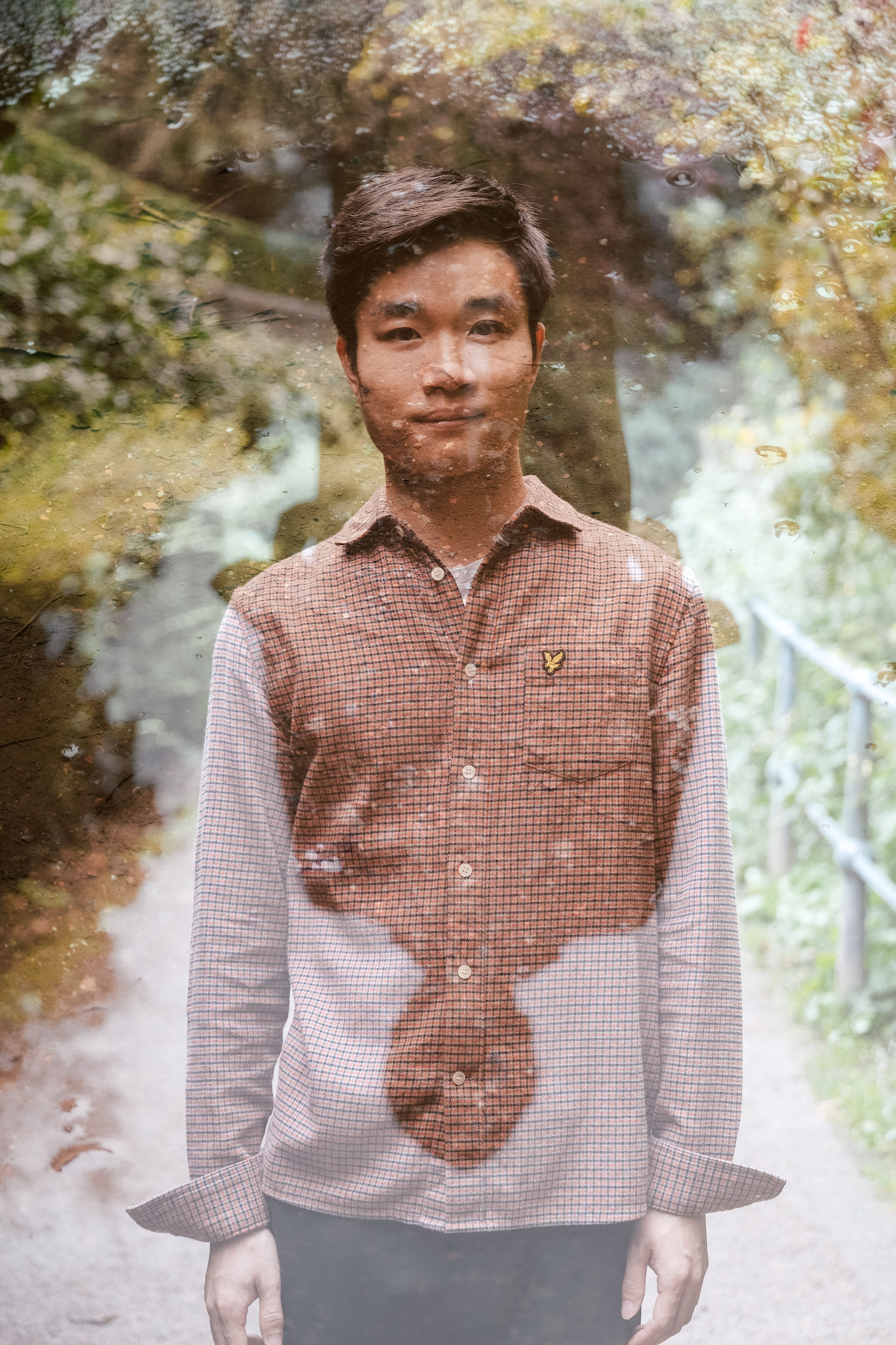 Portrait of a young man in the forest with sunlight filtering through trees.
