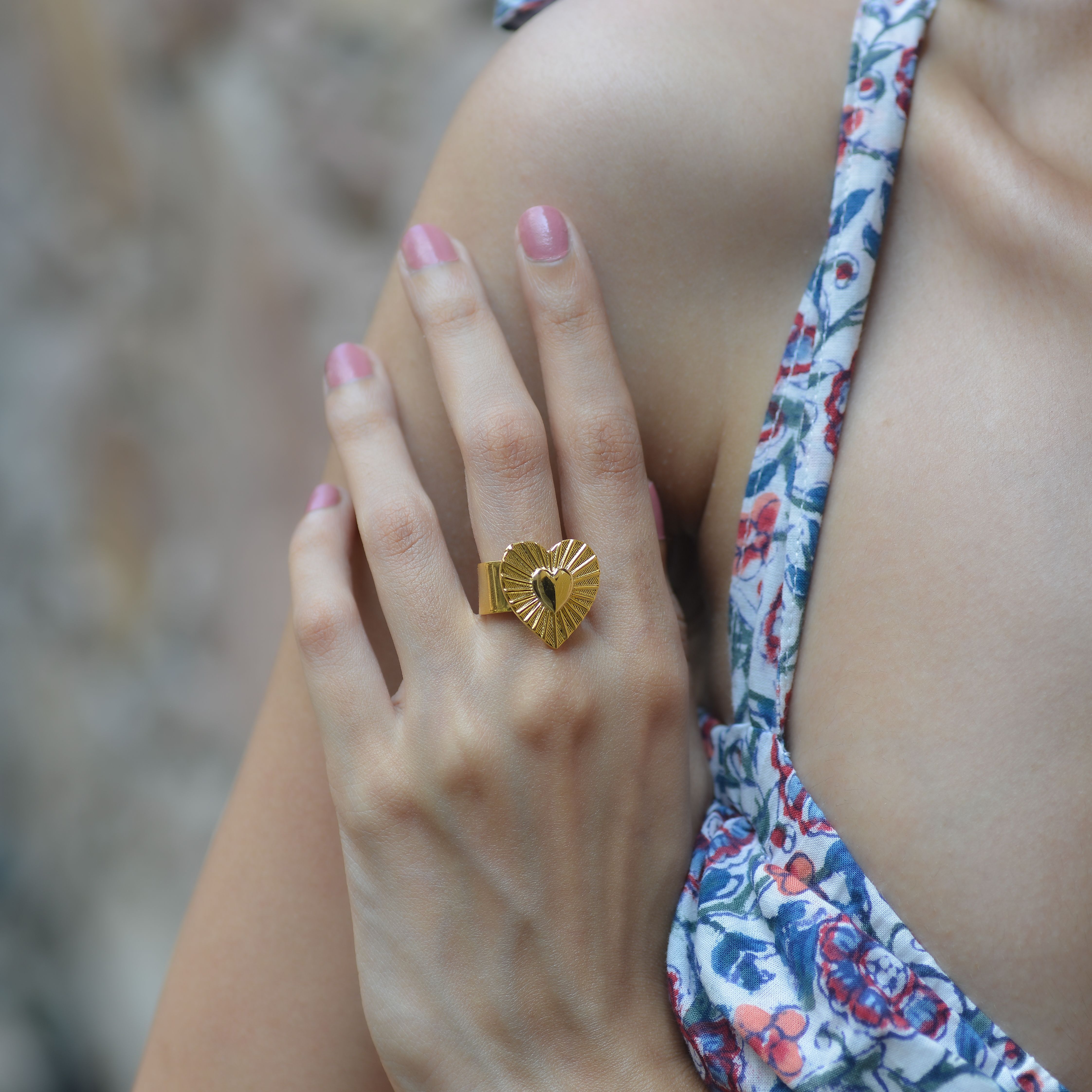 Close-up of a woman's hand wearing an elegant gold heart-shaped ring. Perfect for jewelry and fashion concepts.
