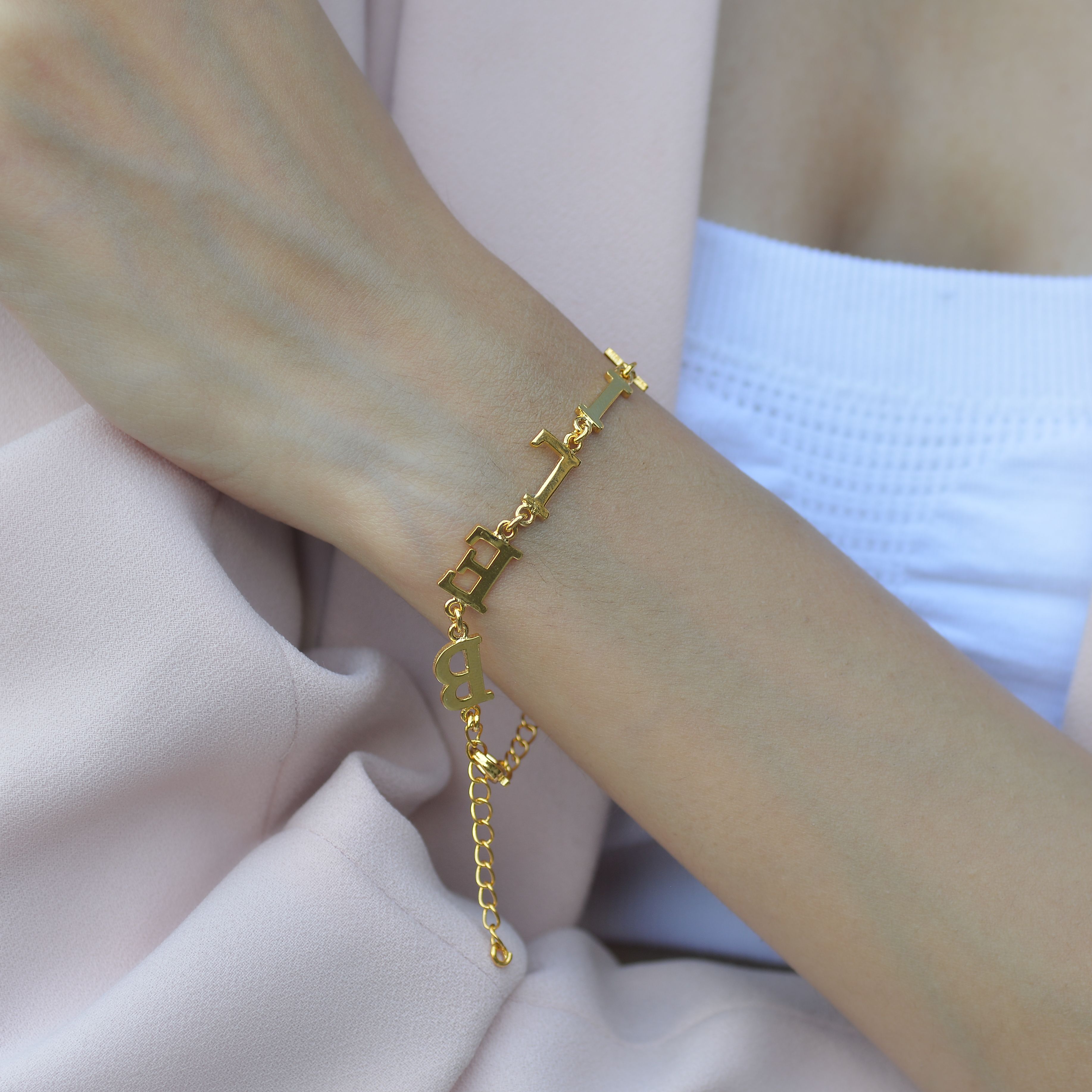 Close-up of a woman's wrist with a gold bracelet, showcasing luxury and elegance in a minimalist style.