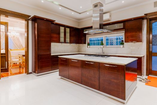 Spacious modern kitchen with wooden cabinets and island, featuring elegant interior design and ambient lighting.
