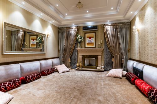 Free Spacious luxurious living room with ornate fireplace, large mirror, and draped curtains. Stock Photo