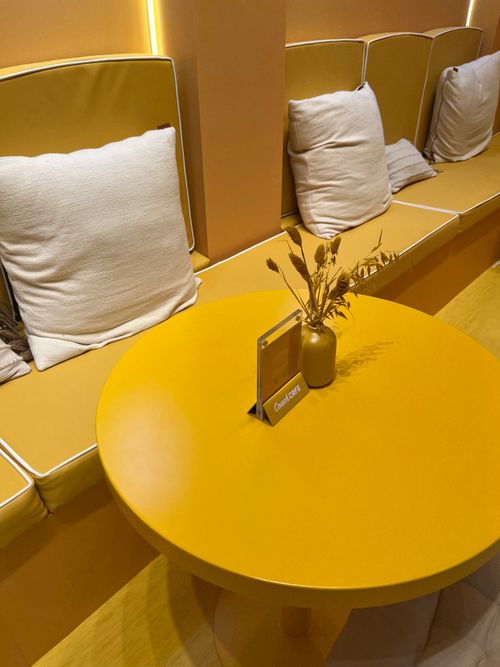 Free Inviting yellow seating area with cushions and table in Dubai café. Stock Photo