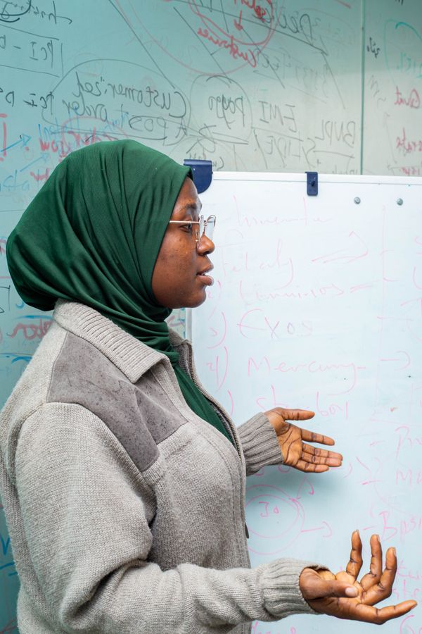Trainer met hoofddoek geeft uitleg bij een whiteboard