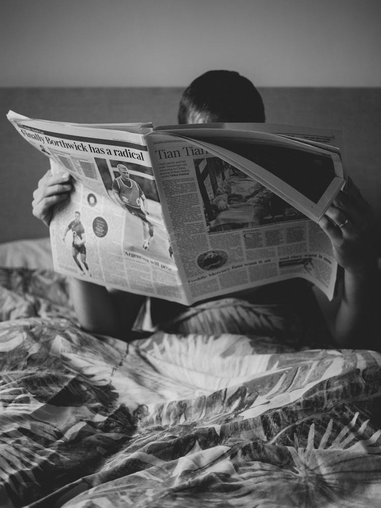 Man Sitting In Bed Reading Newspaper