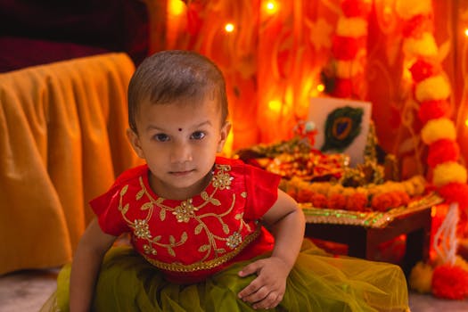 A young child in traditional attire during an Indian festival with bright decorations.