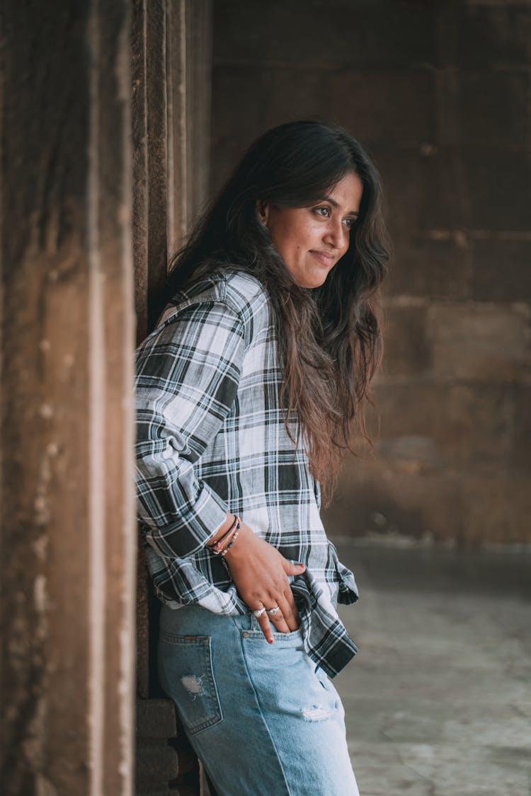 Young Woman In Shirt And Jeans Posing Near Wall