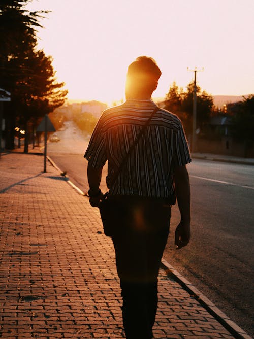 Man Walking on Sidewalk at Sunset