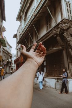 A hand reaches into a bustling street scene in historic Ahmedabad, India, capturing urban life.