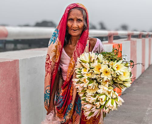 Elderly Woman in Traditional Clothing Standing with Flowers Bouquet