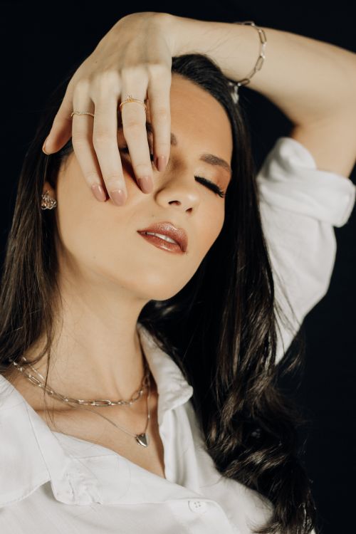 Free Close-up portrait of a woman posing elegantly with eyes closed and hand on face. Stock Photo