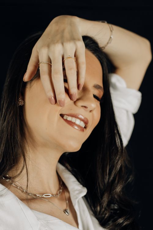 Free A captivating portrait of a smiling woman with long hair and jewelry on a black background. Stock Photo