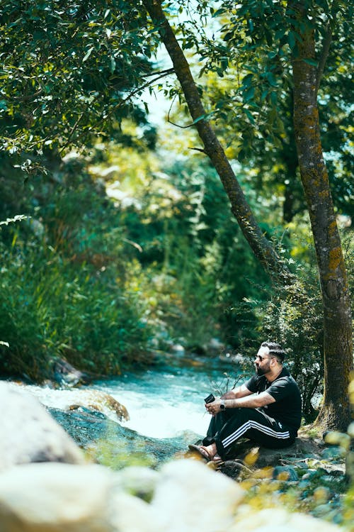 Man Relaxing by River in Forest