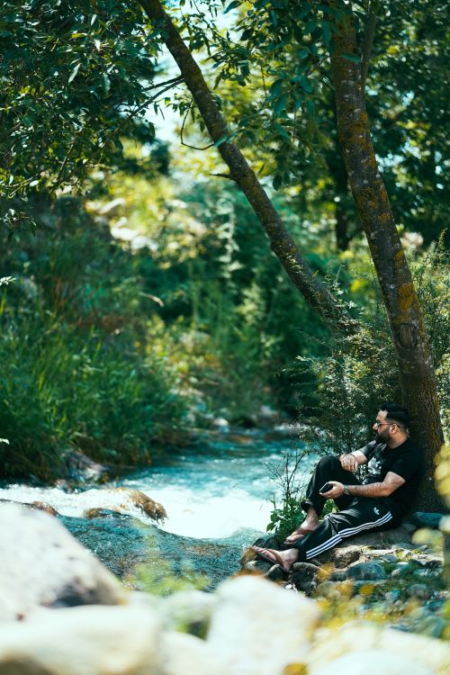 Free A peaceful scene of a man enjoying the tranquility of a forest river on a summer day. Stock Photo