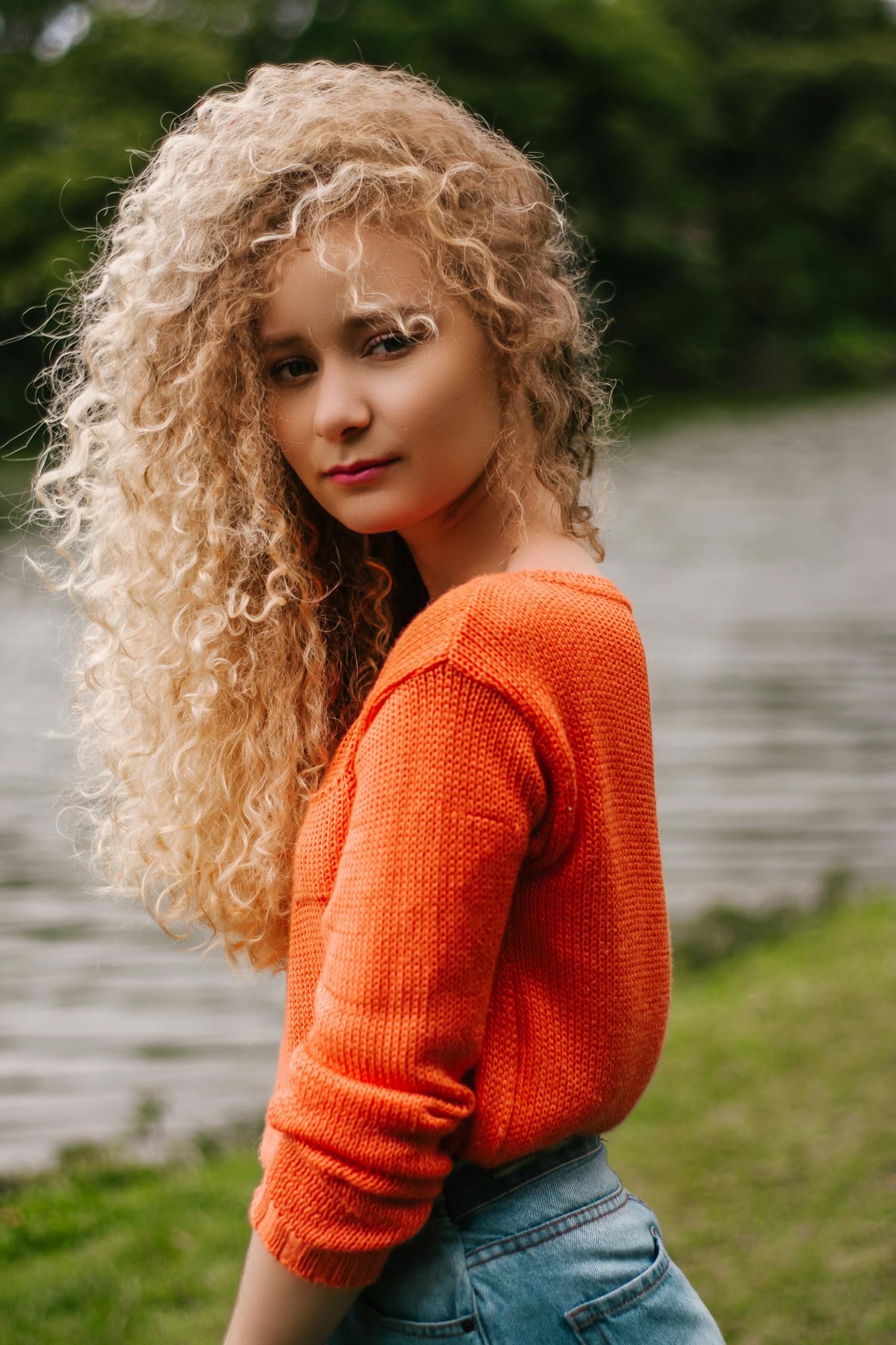 Curly Haired Blond Woman In Orange Shirt Blick Auf Ihre Seite